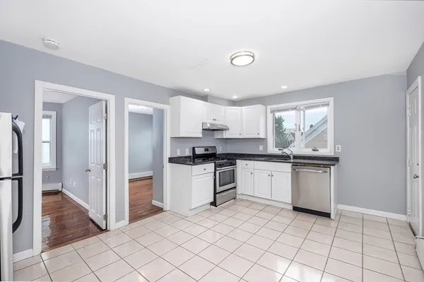 a kitchen with a refrigerator and white cabinets