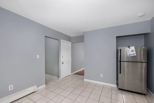a view of a refrigerator in kitchen and empty room
