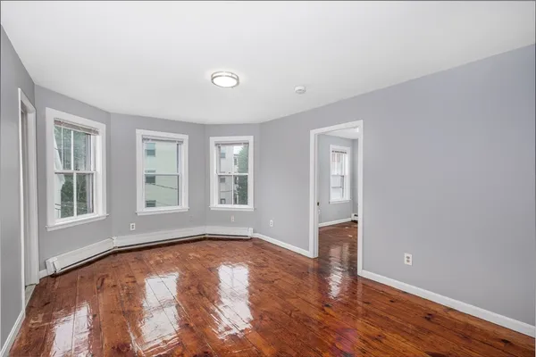 a view of empty room with wooden floor and fan