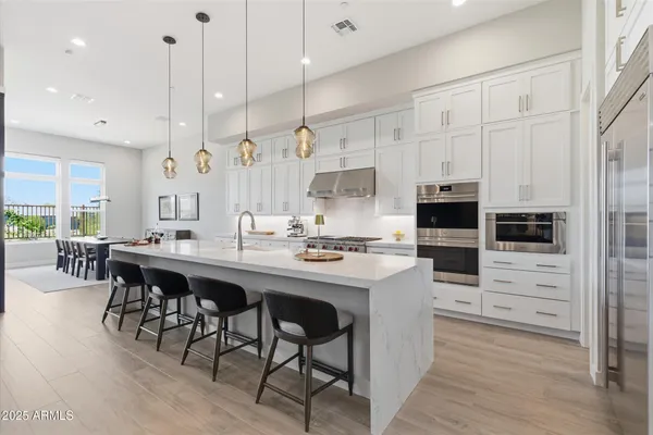 a kitchen with stainless steel appliances kitchen island granite countertop a table chairs sink and cabinets