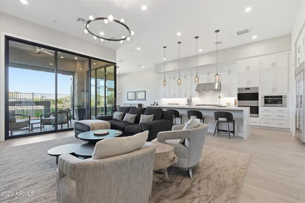 a living room with couches and kitchen view with wooden floor