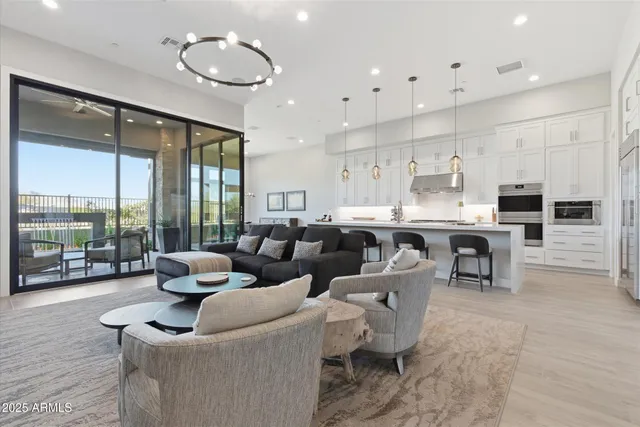 a living room with couches and kitchen view with wooden floor