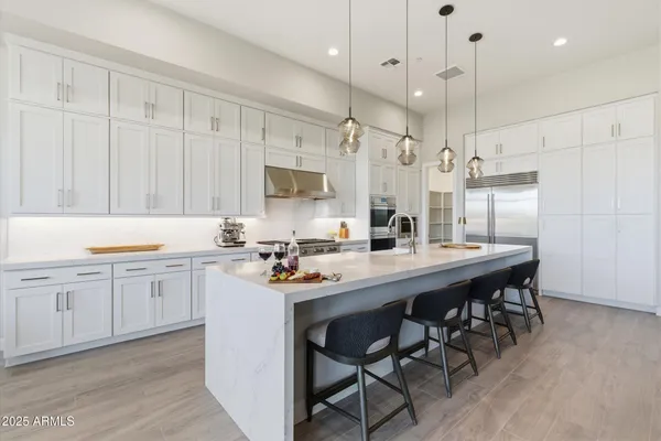 a kitchen with stainless steel appliances kitchen island a table chairs sink and cabinets