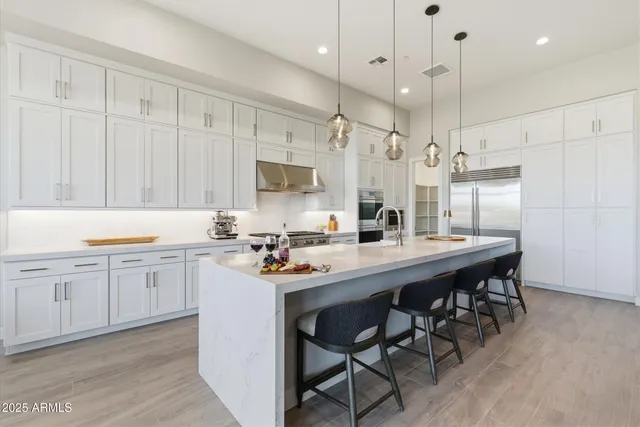 a kitchen with stainless steel appliances kitchen island a table chairs sink and cabinets