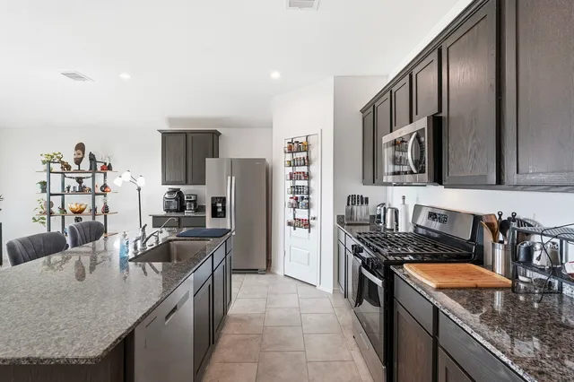 a kitchen with stainless steel appliances granite countertop a sink stove and refrigerator