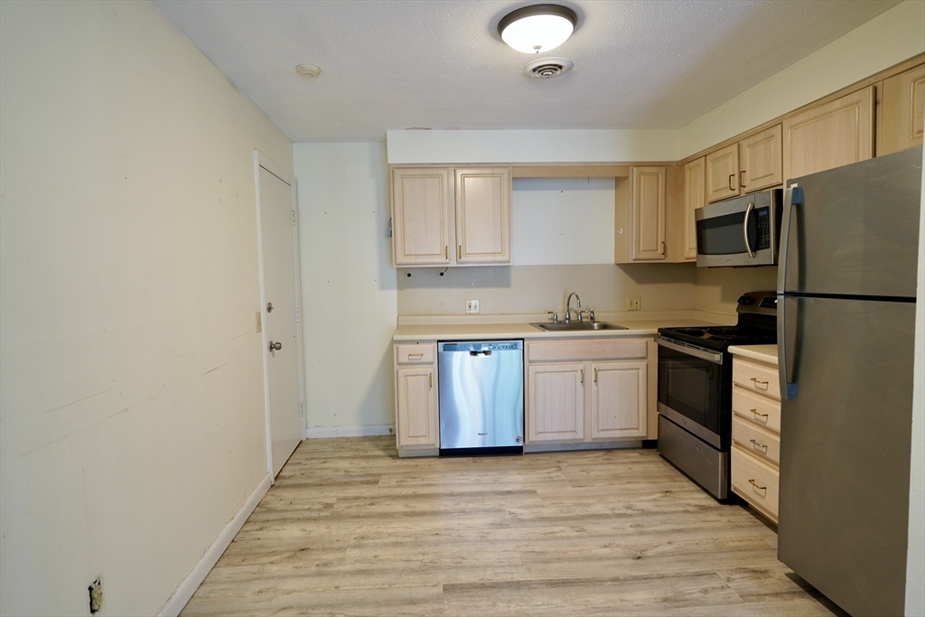 92 Beacon Street, Unit 6 Lawrence, MA 01843 - Photo 4 of 22 a kitchen with a sink a stove top oven and refrigerator