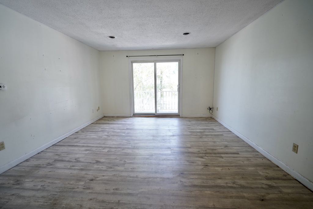 92 Beacon Street, Unit 6 Lawrence, MA 01843 - Photo 6 of 22 a view of an empty room with wooden floor and window