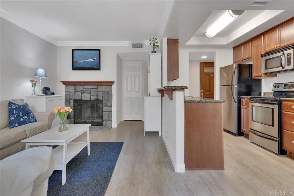 a living room with stainless steel appliances furniture a fireplace and a flat screen tv
