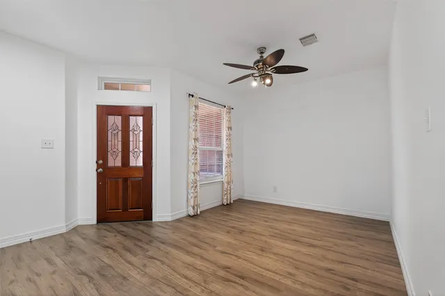 an empty room with wooden floor closet and windows