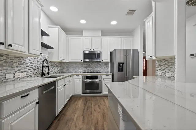 a large kitchen with stainless steel appliances granite countertop a sink stove refrigerator and cabinets