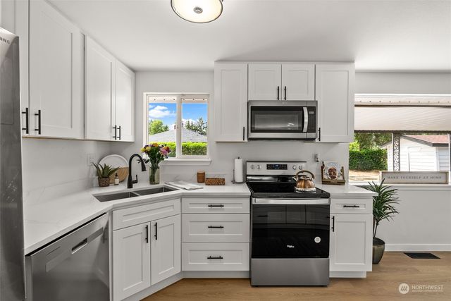 a kitchen with granite countertop white cabinets and stainless steel appliances