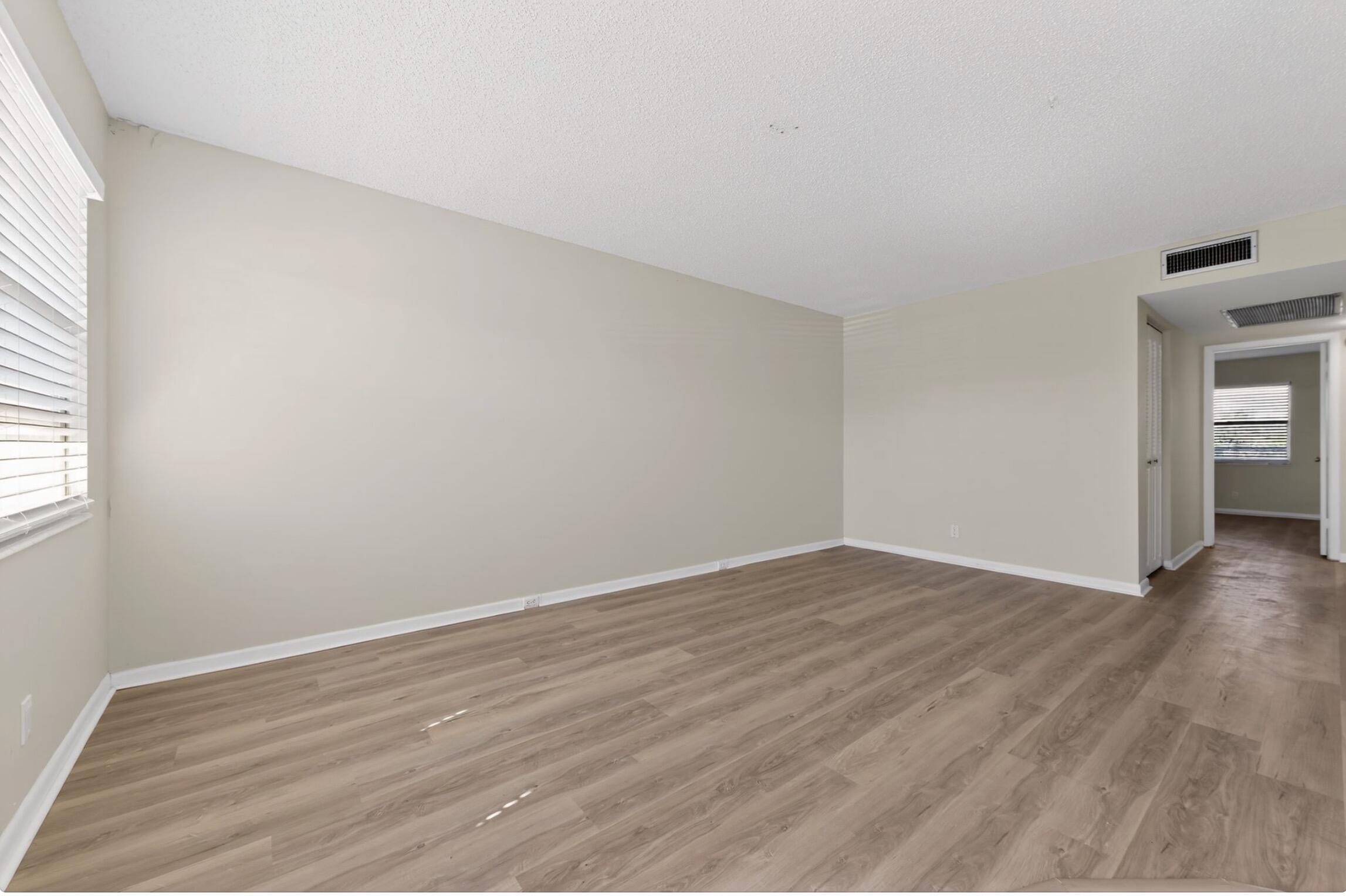 2012 Hythe A, Unit 2012 Boca Raton, FL 33434 - Photo 12 of 15 an empty room with wooden floor and windows
