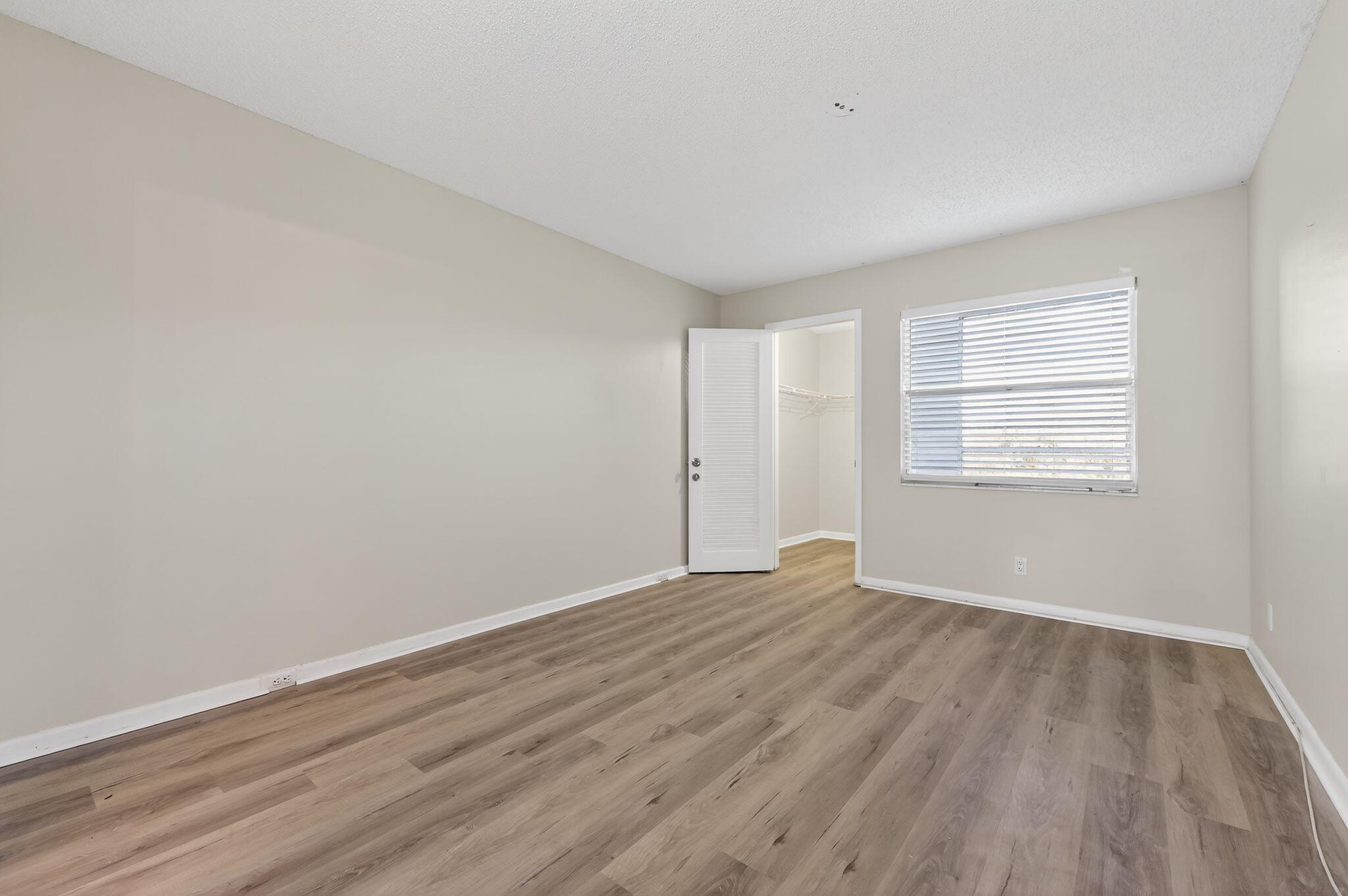 2012 Hythe A, Unit 2012 Boca Raton, FL 33434 - Photo 14 of 15 a view of an empty room with wooden floor and a window