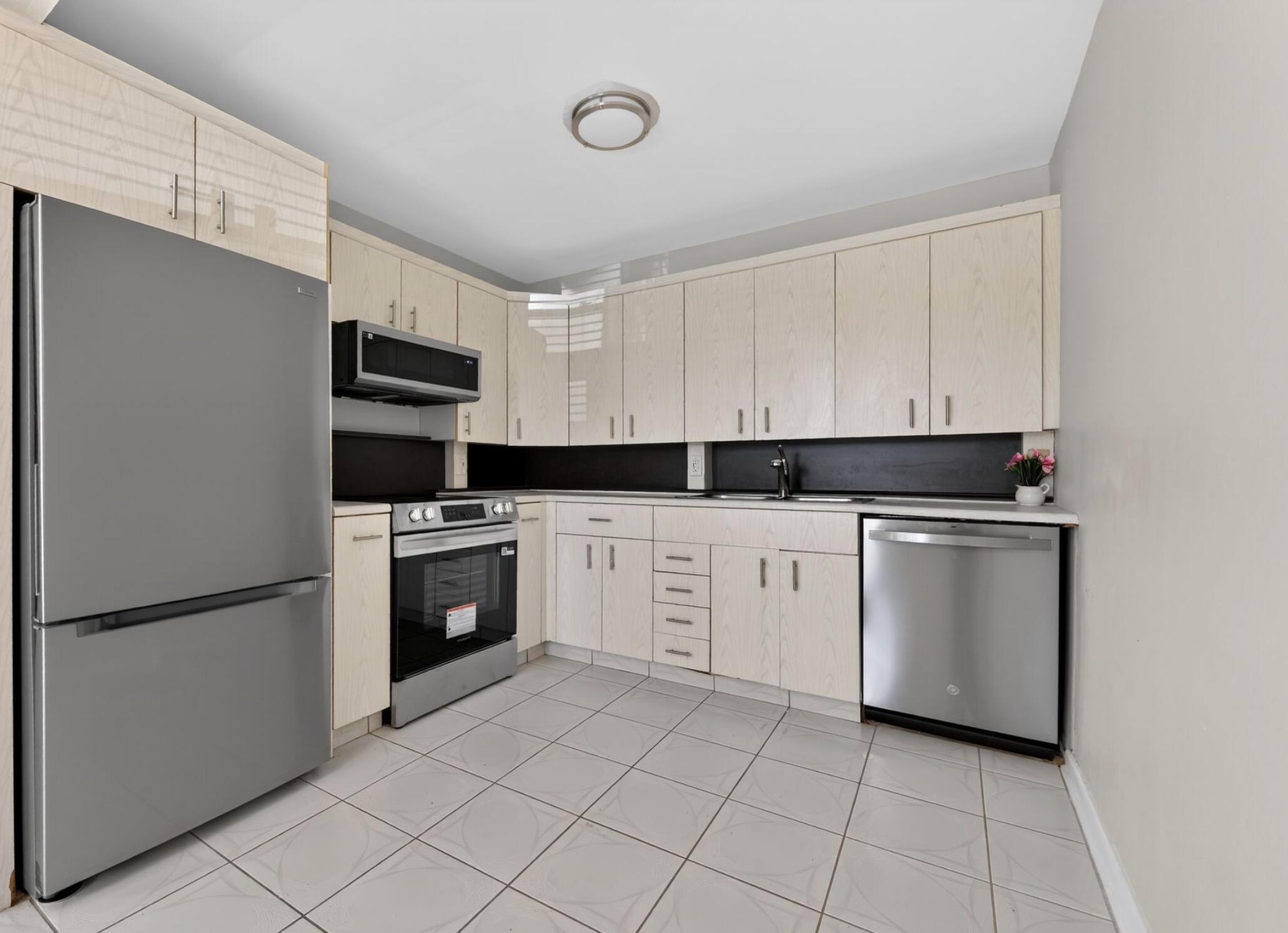 2012 Hythe A, Unit 2012 Boca Raton, FL 33434 - Photo 5 of 15 a kitchen with white cabinets and white appliances