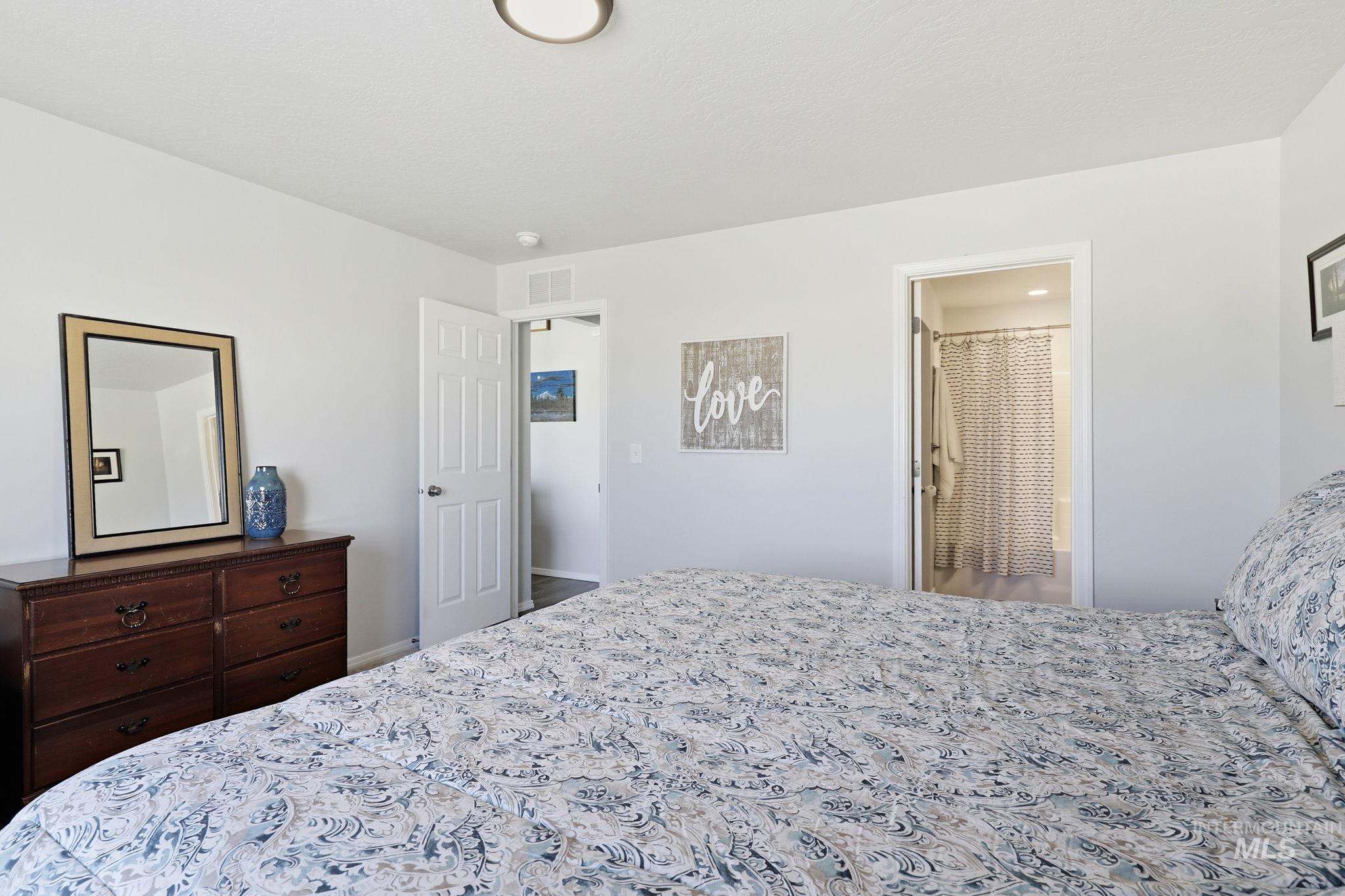 16780 Breton Way Caldwell, ID 83607 - Photo 18 of 28 Spacious bedroom featuring light neutral wall paint, soft carpet flooring, a large window, and an overhead flush-mount light fixture with view of backyard