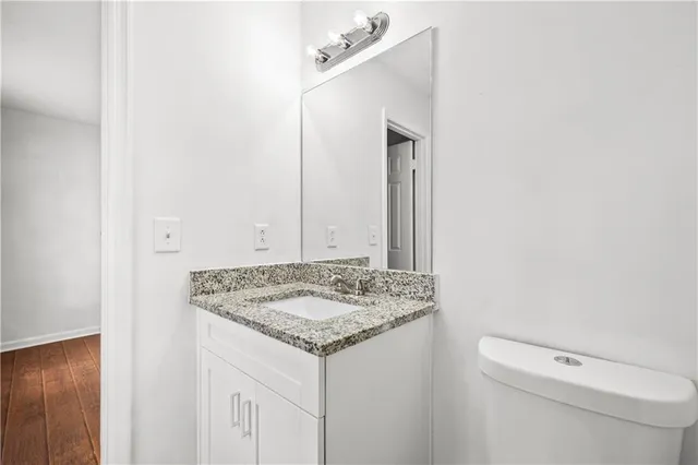 a bathroom with a granite countertop sink and a toilet