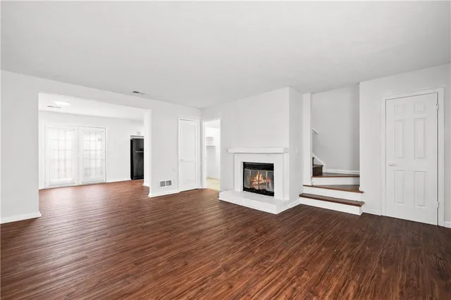a view of an empty room with wooden floor fireplace and a window