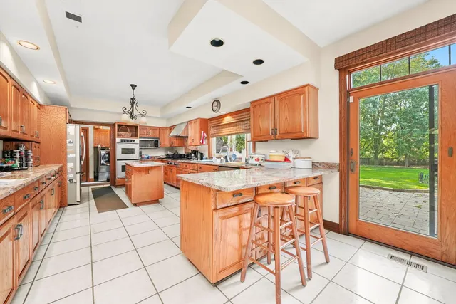 a large kitchen with stainless steel appliances kitchen island granite countertop a table chairs in it and a window