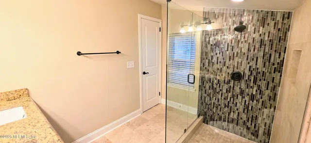 a view of an empty room with window and a chandelier fan