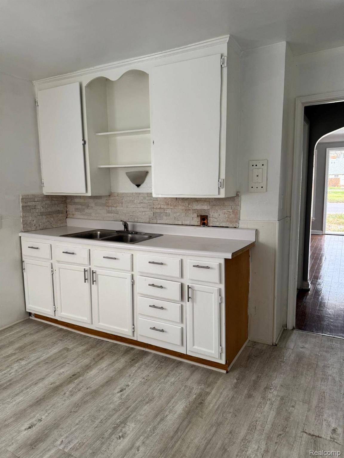 19706 Moross Road Detroit, MI 48224 - Photo 4 of 13 Kitchen featuring white cabinetry with silver hardware, a dual basin stainless steel sink, and light wood-finish flooring
