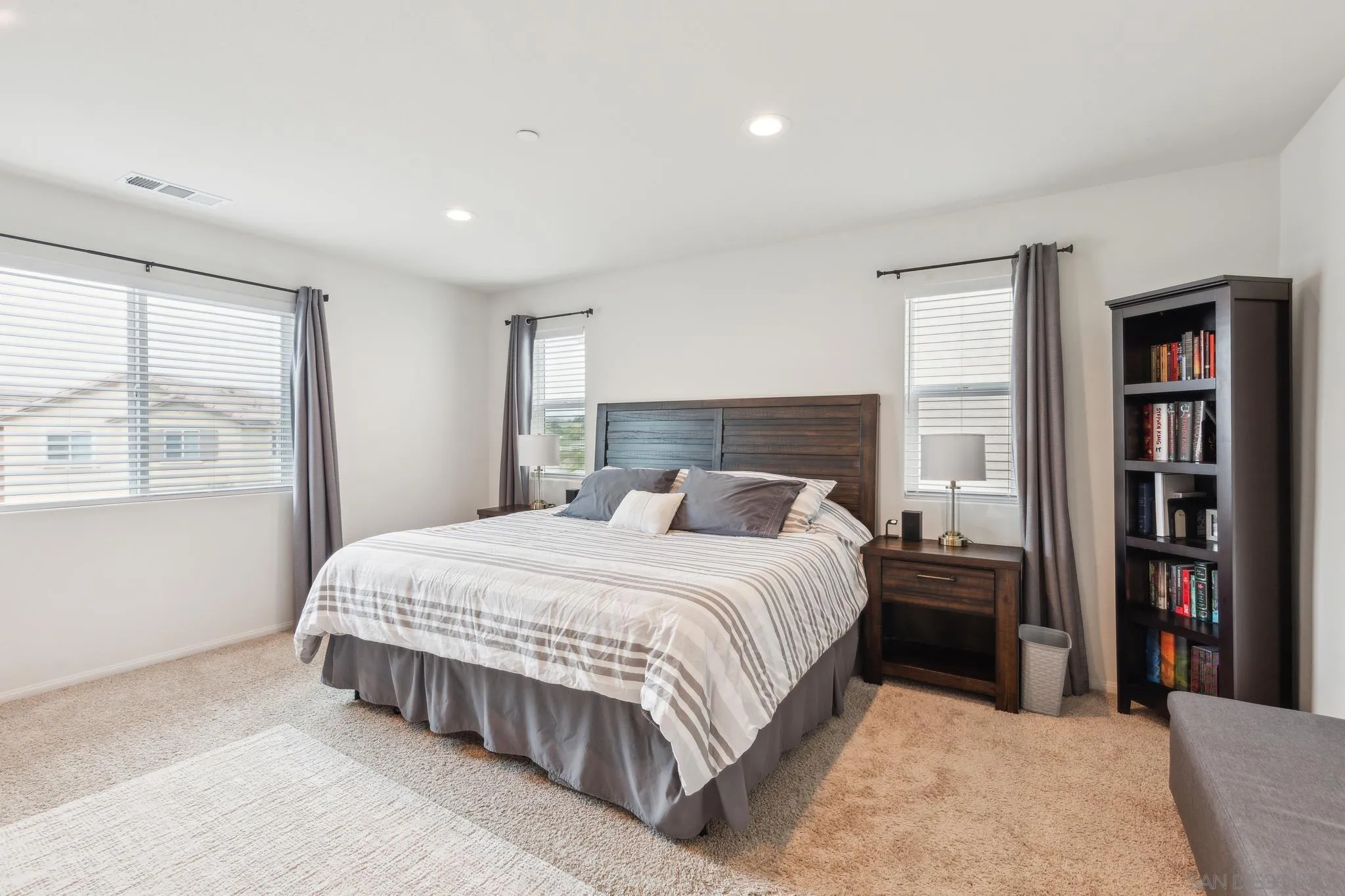 5522 Starlight Place Bonsall, CA 92003 - Photo 16 of 32 a bedroom with a large bed and a book shelf