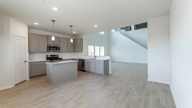 a large kitchen with a sink and dishwasher a stove top oven with wooden floor