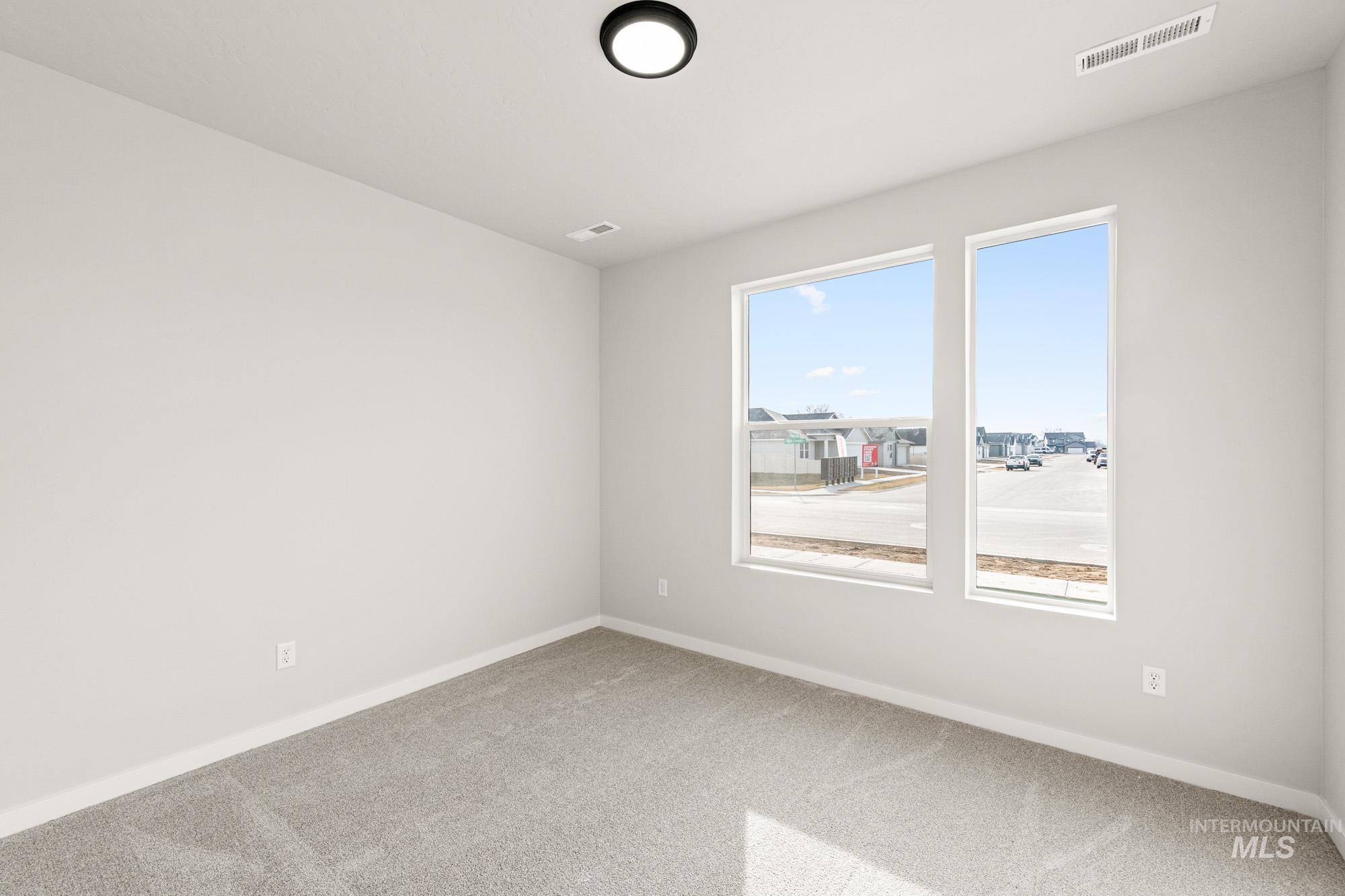 12865 Decatur Street Nampa, ID 83651 - Photo 12 of 20 Bright room featuring two large windows, neutral-toned carpeting, white baseboards, a flush-mount ceiling light fixture, and a ceiling vent