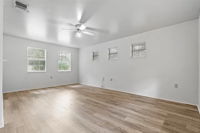 a view of an empty room with wooden floor and a window