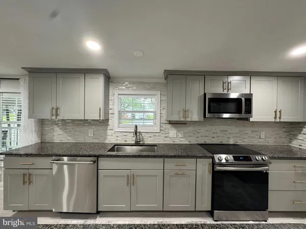a kitchen with granite countertop a sink cabinets and stainless steel appliances