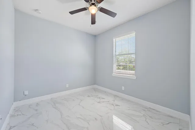 an empty room with a window and a fan