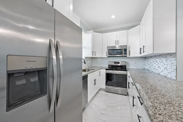 a kitchen with stainless steel appliances granite countertop a refrigerator and a stove top oven