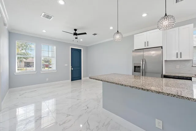 a kitchen with kitchen island granite countertop a center island a sink stainless steel appliances and windows