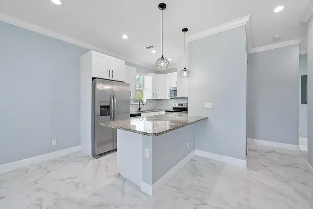 a kitchen with stainless steel appliances granite countertop a sink a stove a refrigerator and island with wooden floor