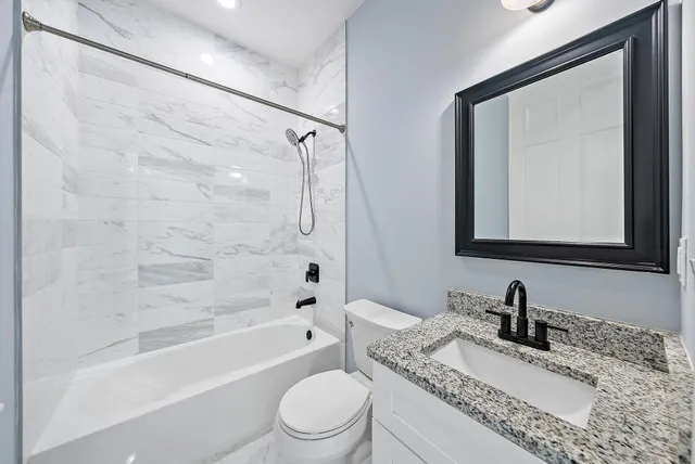 a bathroom with a granite countertop sink toilet mirror and shower