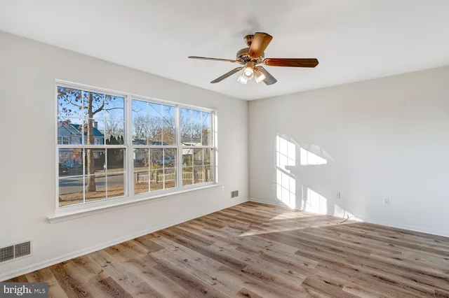 a view of an empty room with a window and wooden floor