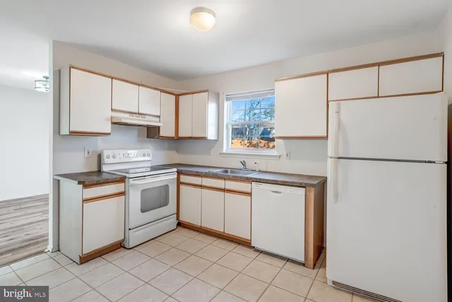 a kitchen with granite countertop cabinets appliances a sink and a window