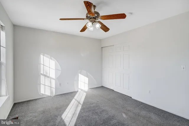 an empty room with windows and fan