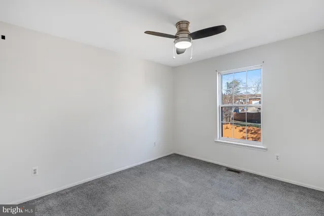 an empty room with a window and a ceiling fan