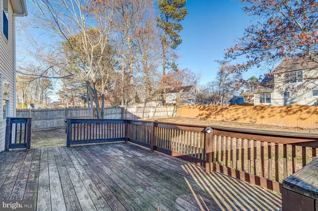 a view of deck with wooden floor and fence with a large tree