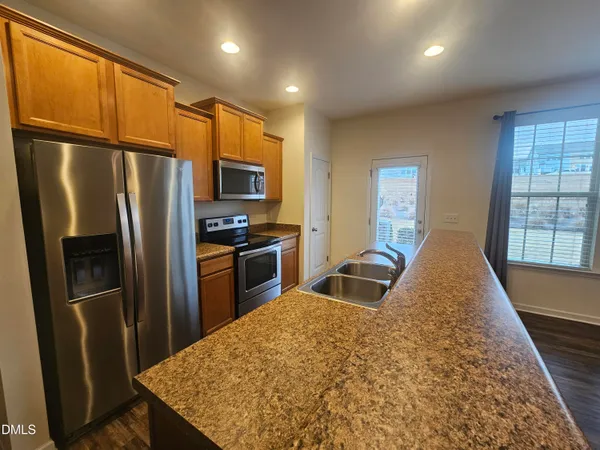 a kitchen with granite countertop a refrigerator and a stove top oven