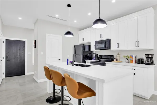 a kitchen with stainless steel appliances a stove a refrigerator and a dining table with white cabinets