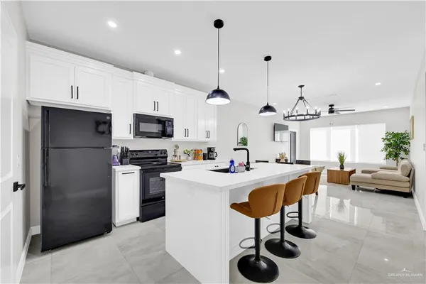 a kitchen with stainless steel appliances granite countertop a sink a stove a refrigerator cabinets and chairs