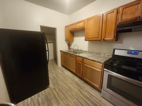 a kitchen with stainless steel appliances granite countertop a refrigerator a stove and a sink with wooden cabinets