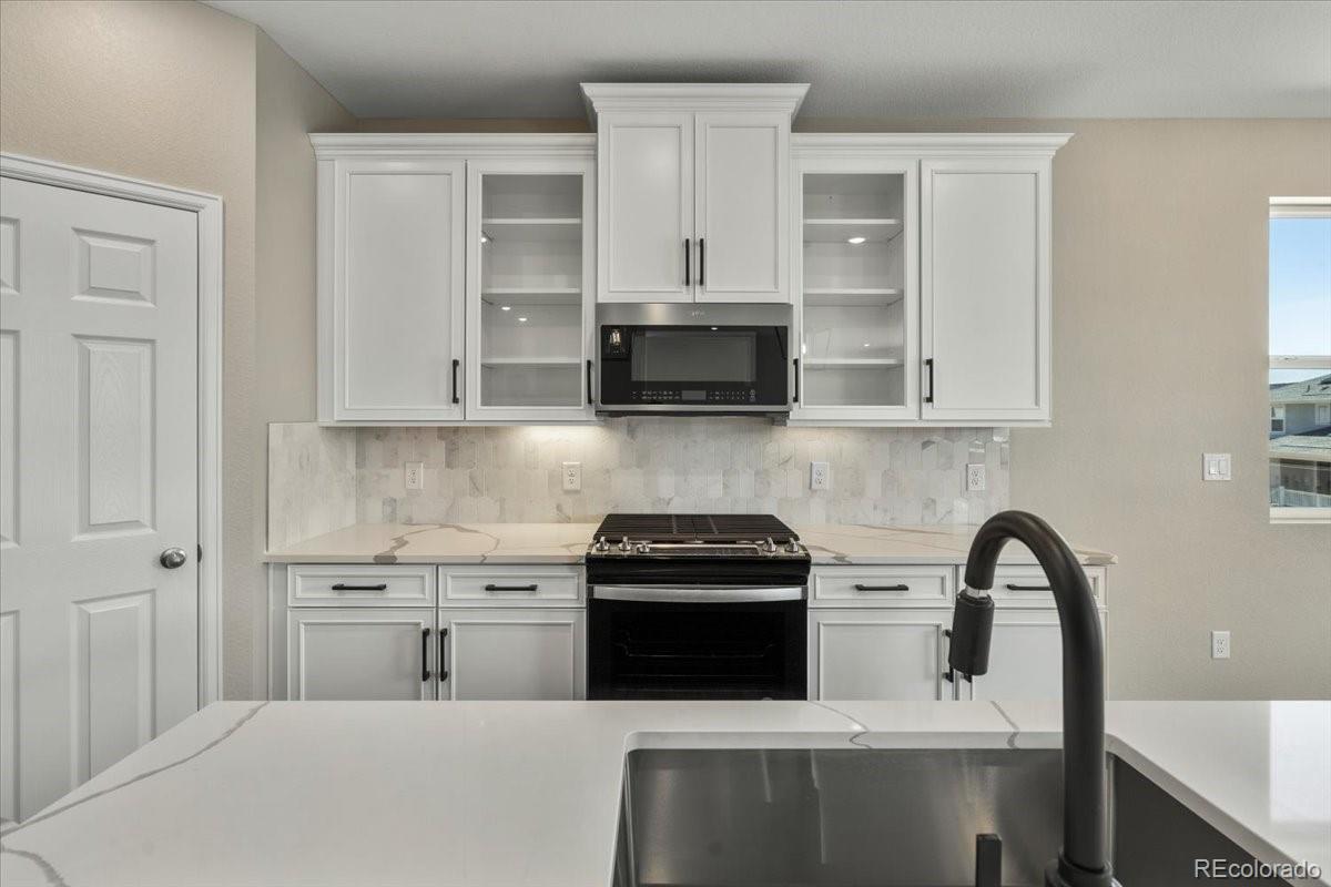 8178 Mount Harvard Road Littleton, CO 80125 - Photo 11 of 39 a kitchen with stainless steel appliances granite countertop a stove a sink and a microwave