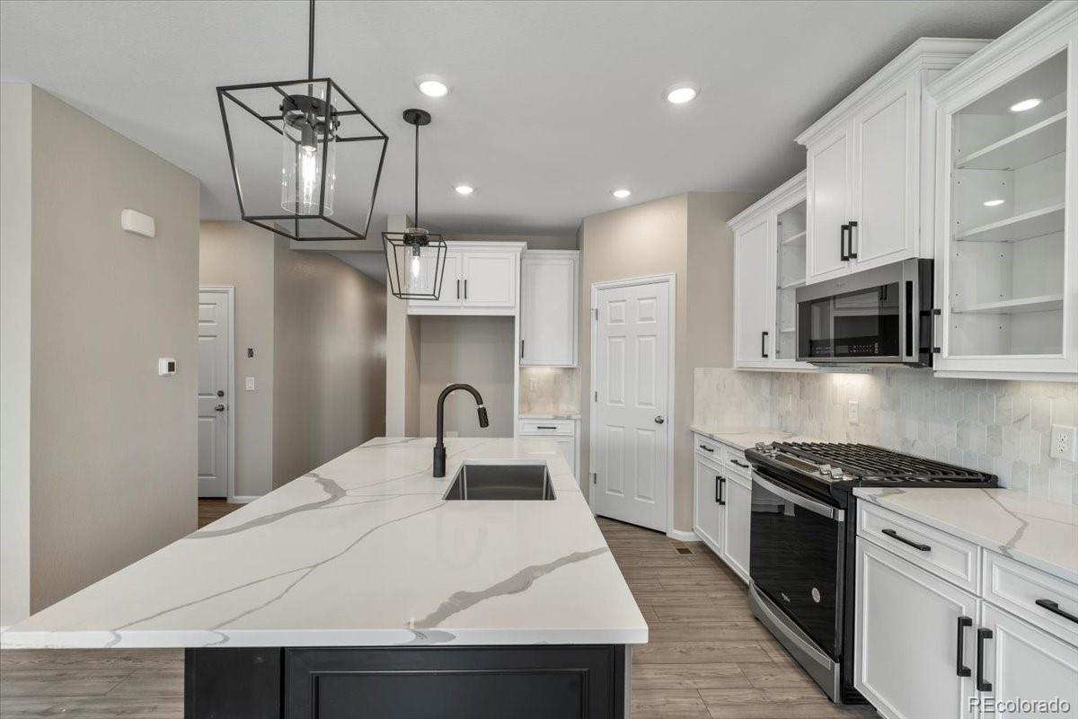 8178 Mount Harvard Road Littleton, CO 80125 - Photo 12 of 39 a kitchen with stainless steel appliances kitchen island granite countertop a stove a sink and a refrigerator