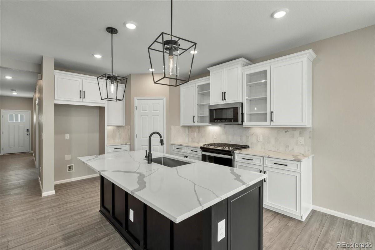 8178 Mount Harvard Road Littleton, CO 80125 - Photo 8 of 39 a kitchen with stainless steel appliances kitchen island a wooden floor and white cabinets