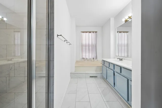 a bathroom with a tub sink shower and mirror