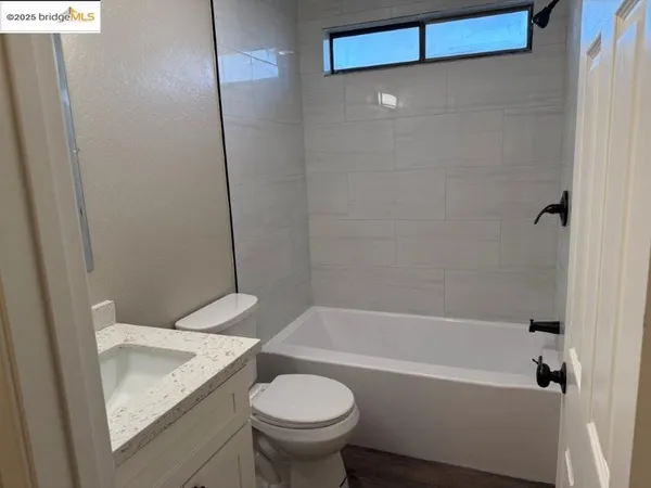 a bathroom with a granite countertop bathtub shower and toilet