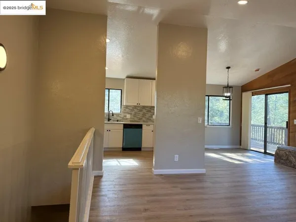 a view of kitchen with empty room and wooden floor