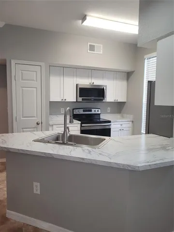 a kitchen with kitchen island a sink stainless steel appliances and a counter top space